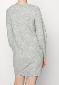 Szara dzianinowa sukienka o teksturowanym wykończeniu, z długimi bufkami i luźnym fasonem, z detalem przy dekolcie z tyłu.