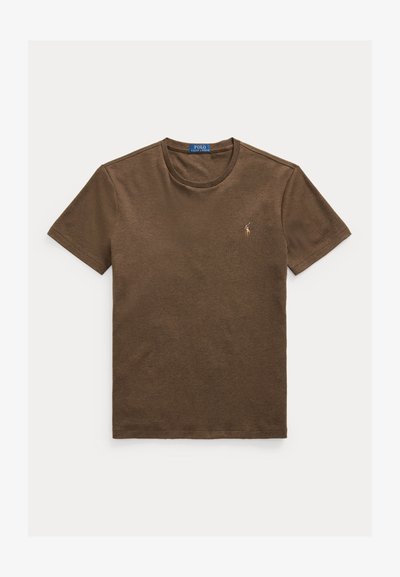 Ruskea puuvillapaita, jossa on pyöreä kaula-aukko ja lyhyet hihat. Vasemmassa rinnassa on pieni brodeerattu logo. Sujuva rakenne.