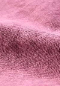 Texturerat tyg i en mjuk mauve-färg, som visar en subtil väv med en ojämn yta som ger djup och intresse.