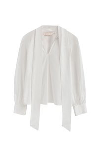 Camicia bianca con lunghi nastri al collo, maniche lunghe a sbuffo e una vestibilità leggermente ampia. Realizzata in un tessuto morbido e liscio.