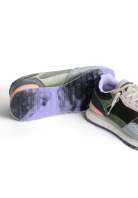 Baskets arborant un mélange de vert foncé, gris et accents pastel. Tige en suède texturé et tissu lisse, avec une semelle en caoutchouc violette.