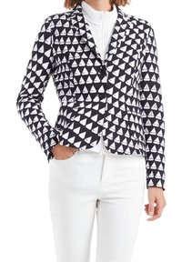 Blazer de patrón en blanco y negro con pequeños triángulos que parecen barcos de vela, con un diseño ajustado, dos botones y un cuello con muesca.