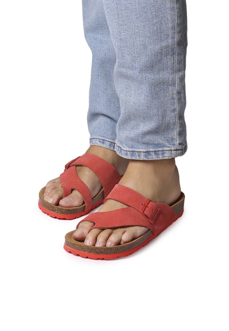 Red suede sandals with crossed straps, adjustable buckle, and cushioned cork footbed. Outsole features textured grip in bright red.