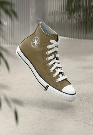 High-top sneaker in olive canvas, featuring white laces, rubber toe cap, and black stripe. Star logo on the side. Textured surface.