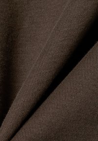 Braunes Strickgewebe mit weicher Textur und feinem Rippmuster. Das Material zeigt einen tiefen schokoladenbraunen Farbton mit dezentem Glanz.