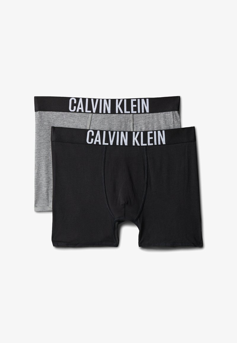 Zwei Paar Calvin Klein Boxershorts, ein schwarzes und ein graues Paar, mit schwarzen Bundbändern mit weißen Calvin Klein Logos.