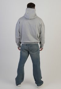 Hanorac gri cu guler înalt și manșete ribbate, combinat cu blugi albastru deschis. Ținuta are o croială lejeră și o textură moale a materialului.