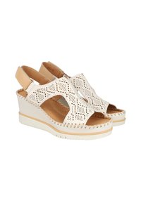 Sandalias de cuña blancas con patrón recortado, parte superior de cuero texturizado y plantilla acolchada en tono tostado. Cuenta con una correa ajustable en el talón y detalle de costuras.