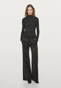 Black long-sleeve turtleneck top paired with wide-leg dark brown corduroy pants. The outfit features a simple, streamlined design.