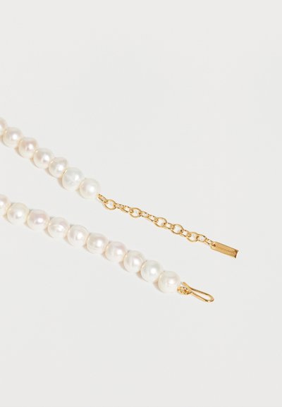 Σειρά από λευκά μαργαριτάρια με χρυσή αλυσίδα επέκτασης και κούμπωμα γάντζου σε λευκό φόντο.