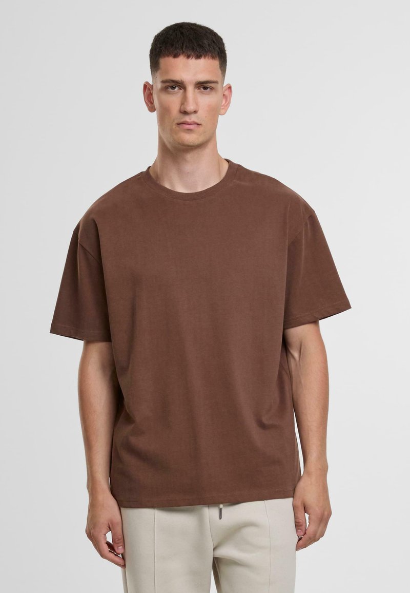 T-shirt marron à manches courtes avec un col rond, en tissu doux. Présente une coupe décontractée et une couleur unie sans motifs ni embellissements.