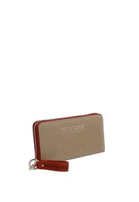 Cartera de piel beige con un cierre rojo, logo dorado en la parte frontal y una correa de muñeca marrón a juego. Forma rectangular, textura suave.