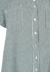 Striped shirt made of cotton, featuring green and white vertical stripes, a button-down front, and two chest pockets. Brown and white buttons.