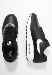 Baskets en cuir noir avec un logo swoosh blanc et des accents. Comprend une unité de coussin Air Max, une semelle texturée et un système de laçage standard.