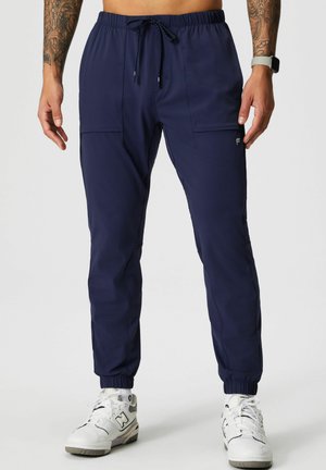 Marineblauwe joggingbroek gemaakt van lichtgewicht materiaal, met een elastische tailleband met trekkoord, twee voorzakken en elastische manchetten.