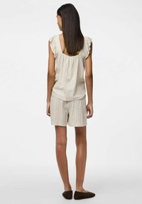 Top senza maniche beige a righe con maniche arricciate, abbinato a pantaloni corti a righe coordinati. Tessuto morbido con una vestibilità comoda. Scarpe beige slip-on.