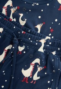 Navy pajama set featuring white ducks with red scarves and blue hats, accented with stars and snowflakes, gathered waistband with a drawstring.