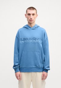 Felpa con cappuccio blu chiaro, dotata di grande logo "HUGO" ricamato, tasca frontale e polsini a costine. Realizzata in tessuto morbido e texturizzato.