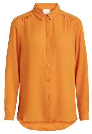 Pomarańczowa bluzka z długim rękawem, z ostrym kołnierzem i guzikami z przodu, lekko marszczona na szwach ramion i z zakrzywionym dołem.