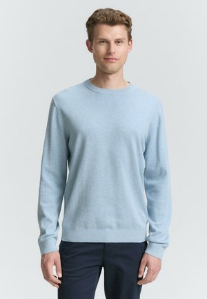 Lichtblauwe crewneck trui van zachte stof, met lange mouwen en geribde boorden en onderrand. Gecombineerd met een donkere broek.