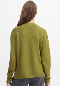 Olijfgroene gemêleerde trui met een losse pasvorm, geribbelde manchetten en zoom; heeft een brede halslijn en een patronen breimotief.