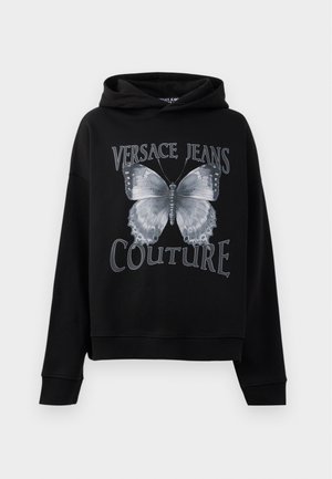 Čierna mikina s kapucňou vyrobená z jemnej tkaniny, ktorá má na sebe veľký šedý motýľ a text "VERSACE JEANS COUTURE" v tučnom písme.