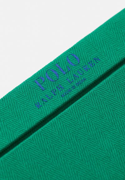 Detaj majice s kratkimi rokavi v svetlo zeleni barvi iz teksturiranega pletenja, ki ima modro vezeno logo "POLO RALPH LAUREN" blizu izreza.