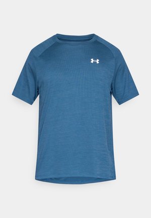 Zils sporta krekls ar īsām piedurknēm, teksturētu virsmu un apaļu apkakli. Kreisajā krūšu daļā ir balts logotips. Mīksts, elpojošs materiāls.