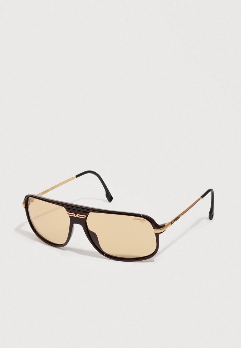 Brazna in zlata Carrera sončna očala v stilu aviator z zatemnjenimi lečami in črnimi ušesnimi ročaji na belem ozadju.