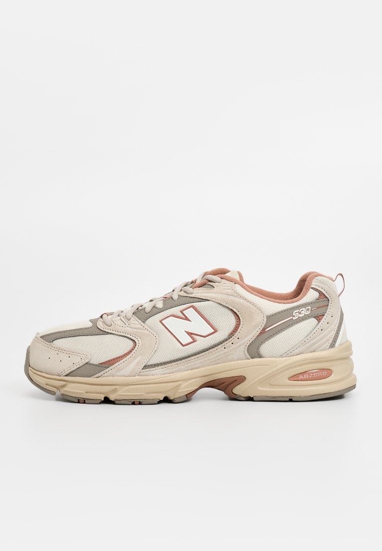Baskets de sport beiges en matériaux en maille et en suède, avec un logo "N" blanc, des accents roses et une semelle en caoutchouc texturée. Numéro de modèle 530.