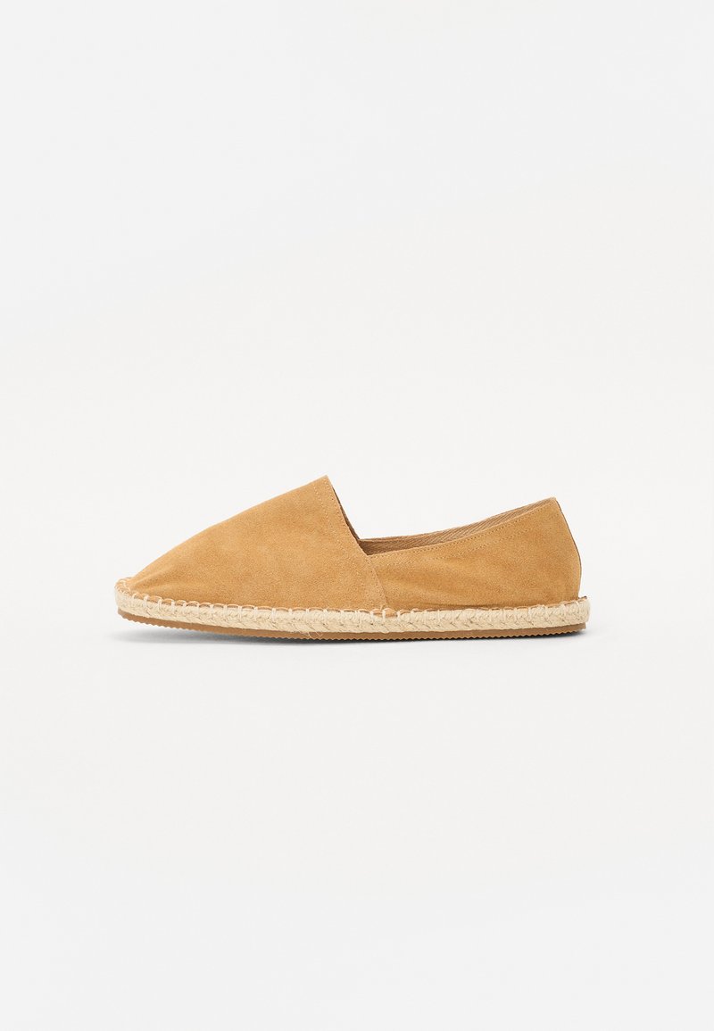 Espadrille en daim de couleur brun clair, avec un bout pointu et une semelle en corde de jute naturel. Design minimaliste sans matériel ou accents supplémentaires.