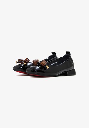 Chaussures en cuir verni noir avec un petit talon et un bout rond. Présente deux nœuds brun à motifs avec des accents dorés sur le dessus. Semelle rouge.