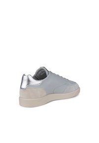 Grå lädersneaker med en mocka beige häl och en metallisk silverdetalj. Har platta snörningar och en texturerad inredning.