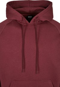 Bordeaux hoodie lavet af blødt stof med en kængurulomme, snoretræk i hætten og raglanærmer for en afslappet pasform.