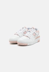 White leather sneakers with light pink accents, perforated sides, and a textured sole. Features a lace-up design and logo details.