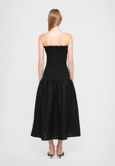 Zwarte strapless jurk met een smocked, aansluitend lijfje en een vloeiende, geplooide rok. Gladde textuur en lengte tot halverwege de kuit. Eenvoudig ontwerp.