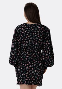 Svart blommig klänning med långa ärmar, cinchad midja och ett mönster av rosa och gröna blommor mot en mörk bakgrund.