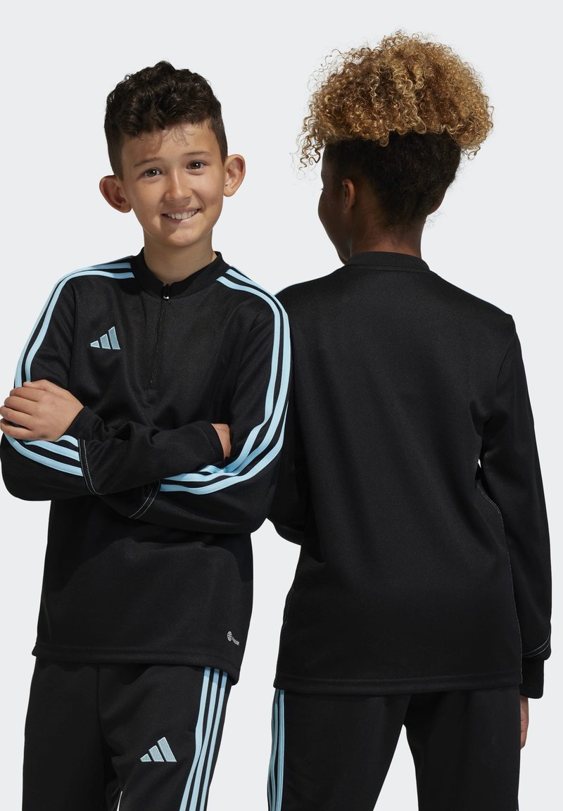 Haut de sport noir avec des accents bleus et une demi-fermeture éclair. Fabriqué en tissu lisse, il présente des manches longues et un pantalon assorti avec des rayures.