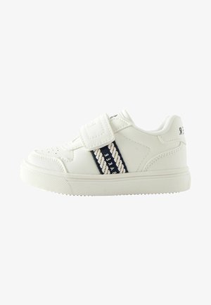 Biele syntetické tenisky s textúrovanou podrážkou, vybavené pásikom na suchý zips a námorníckymi pruhmi s textovým detailom po stranách.