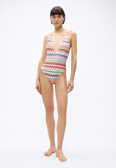Jednoczęściowy kostium kąpielowy z głębokim dekoltem w kształcie litery V, wielokolorowym wzorem w zygzaki i cienkimi ramiączkami; wykonany z gładkiego, elastycznego materiału.