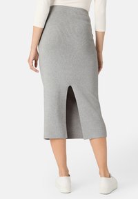 Šedá žebrovaná pletená midi sukně s elastickým pasem a předním rozparkem. V kombinaci s bílými teniskami. Hladká textura a přiléhavý design.