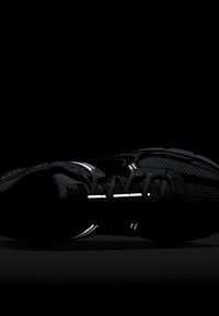 Črne tekaške čevlje z mrežnim zgornjim delom, odsevnimi poudarki in teksturiranim podplatom. Imajo vezalke in značilni swoosh logotip.