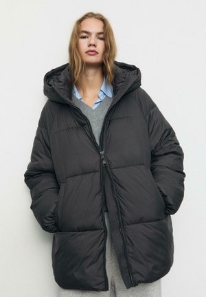 Schwarze gepolsterte Daunenjacke mit Reißverschluss, Kapuze und weiter Passform. Sie hat eine glatte Textur und gestickte Details am Körper.