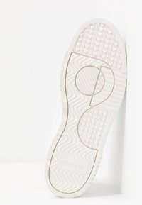 White Adidas sneaker sole with textured patterns, grooves, and Adidas logo embossed near the heel, photographed against a white background.