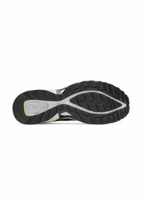 Black athletic shoe sole with textured rubber surface, featuring pronounced treads and a silver midsole accent. Inner side shows bright yellow detail.