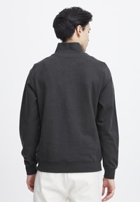 Donkergrijze pullover sweatshirt met een hoge kraag, ribbelmanchetten en -zoom; gemaakt van zachte stof met een gladde textuur.
