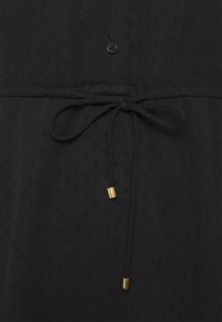 Schwarzes Kleid mit strukturiertem Stoff, Knopfverschluss und Kordelzug in der Taille mit goldenen Akzenten. Einfaches, elegantes Design mit dezenten Mustern.