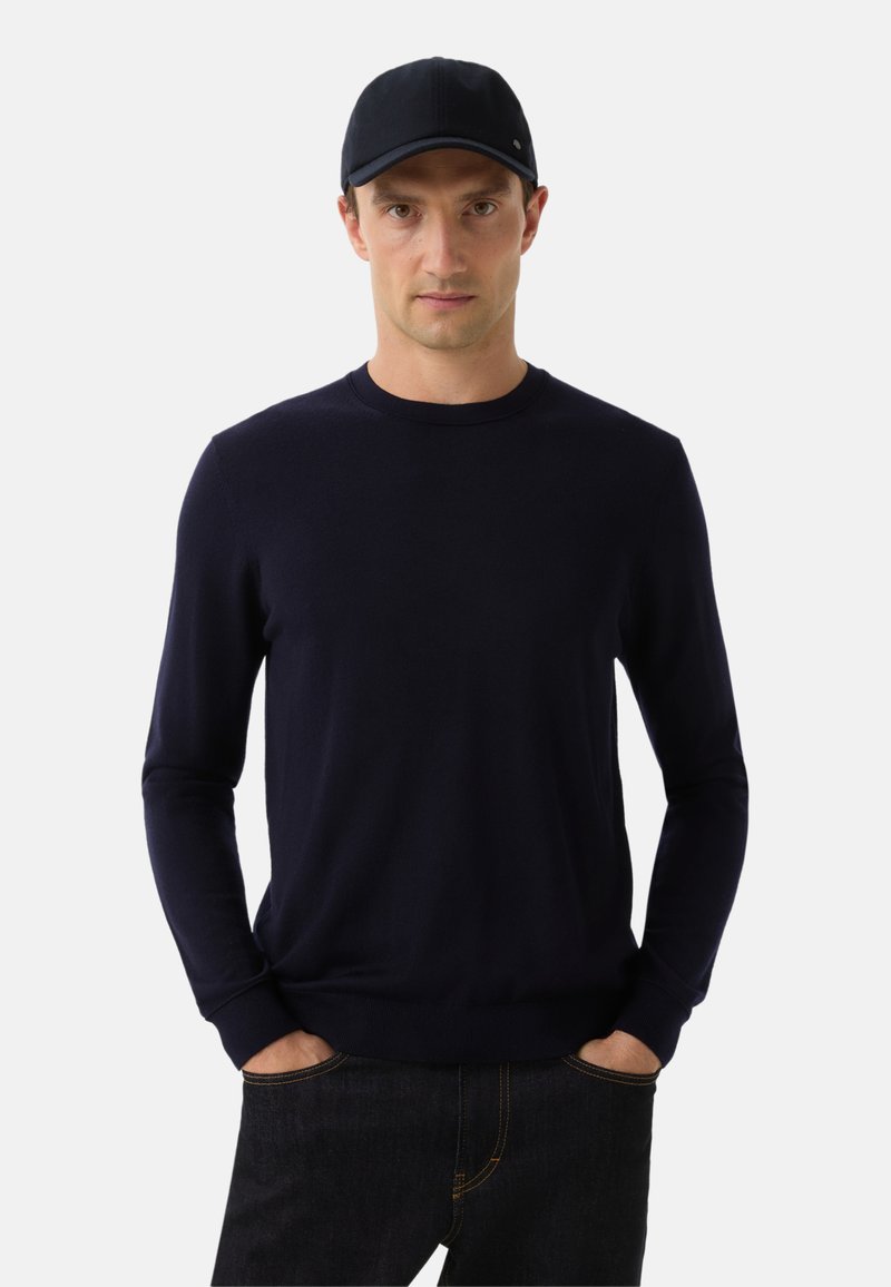 Námořnická modrá dlouhá svetr z měkké pleteniny, doplněný odpovídající čepicí. Úzký střih, kulatý výstřih a ribbované manžety.