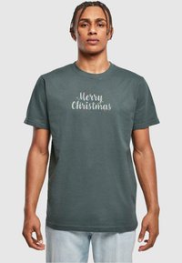Mørkegrøn bomulds t-shirt med korte ærmer; har "Glædelig Jul" tekst i lys grå med farverige detaljer. Casual pasform, rund halsudskæring.