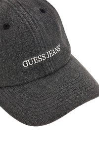 Black denim baseball cap with a curved brim, featuring embroidered "GUESS JEANS" logo in white, subtle texture, and stitched detailing on the brim.